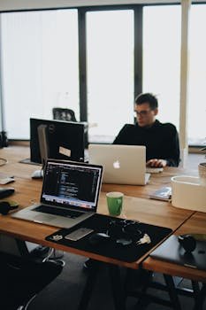 Home A web developer working on code in a modern office setting with multiple devices.