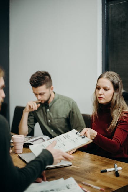 Home A team of adults discussing documents in an office meeting setting, focusing on collaboration.